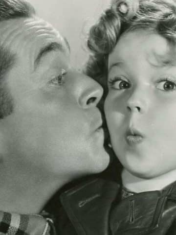 James Dunn kissing Shirley Temple on the cheek in Bright Eyes publicity photo