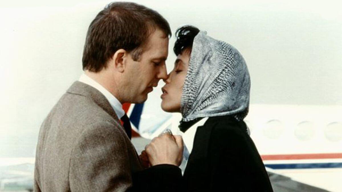 the bodyguard review featured image with Kevin Costner and Whitney Houston about to kiss.
