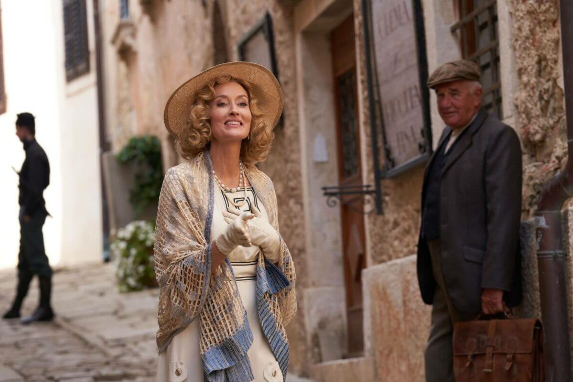 Bella in Hotel Portofino Season 2 walking down a street and smiling. She's dressed in 1920s fashion. 