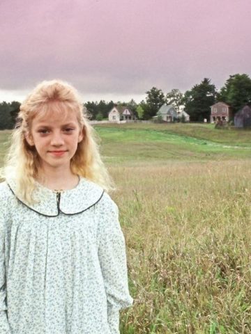 Sara Stanley in Avonlea standing in a meadow with the King family standing in a distance behind her. The image is for a period drama review of Road to Avonlea Series.