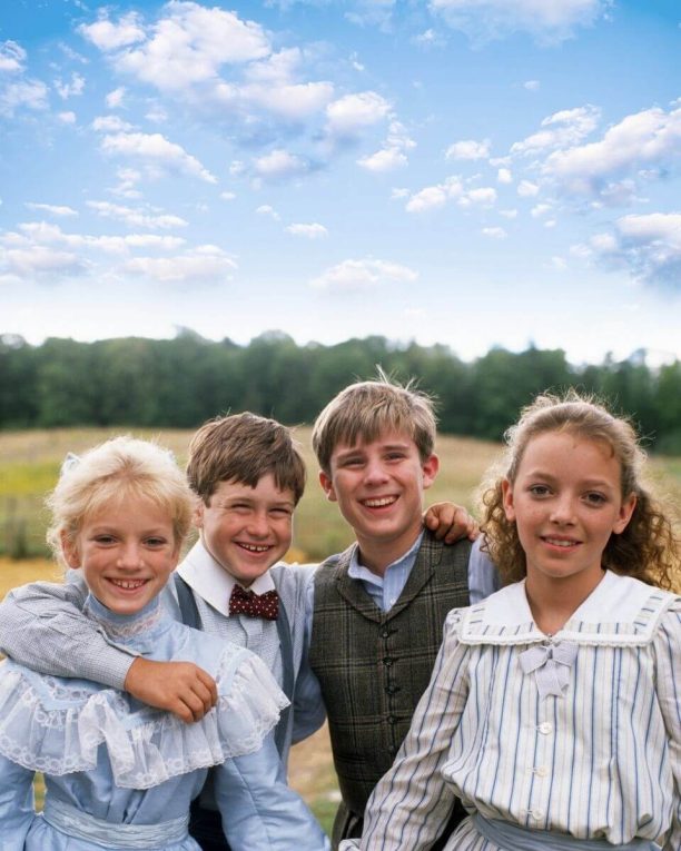Sara, Felix, Andrew, and Felicity in Avonlea standing in a meadow posing for a photo.